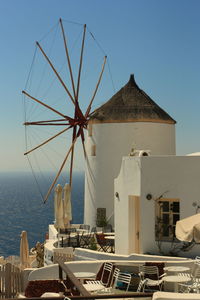 Traditional windmill by sea against clear sky