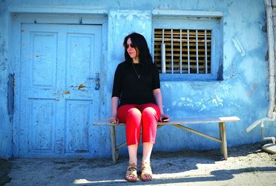 Full length of woman sitting in front of building