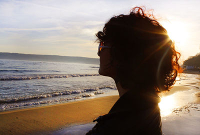 Side view of woman looking at sea during sunset