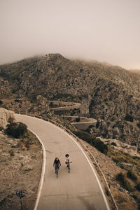 High angle view of male and female friends cycling on road against mountains