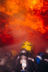 Rear view of firefighters spraying water on fire