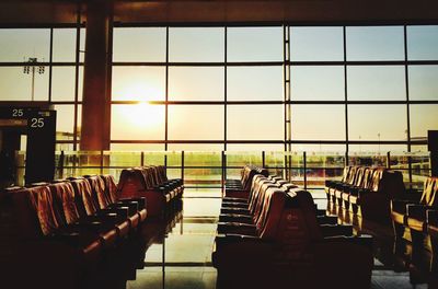 Empty chairs at airport against sky during sunset