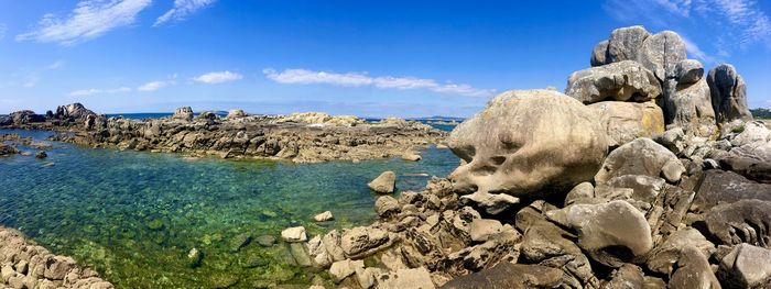 Panoramic view of rocks on shore against blue sky