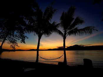Silhouette palm tree by sea against sky during sunset