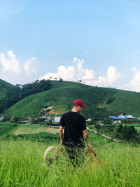 Rear view of man with dog standing on field against sky