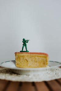 Toy soldier standing on the top of a piece of cake - close up of figurine aginst white background