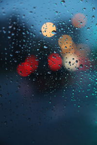 Close-up of raindrops on car window at dusk