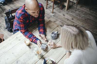 High angle view of multi-ethnic couple using mobile phone in coffee shop