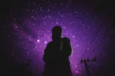 Silhouette woman standing against illuminated lights at night