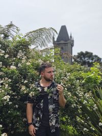Low section of man holding plant in a garden in front of a castle