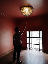 Rear view of man standing against illuminated ceiling