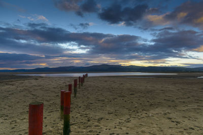 View of calm beach against cloudy sky