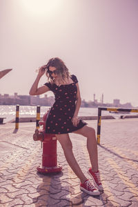 Low angle view of woman leaning on water pump against sky