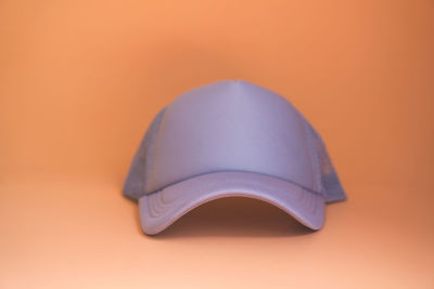 Close-up of hat on table against orange background