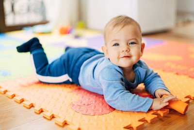 Portrait of cute baby lying on floor at home