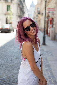 Portrait of woman wearing sunglasses standing on street in city