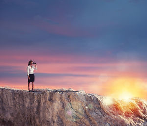 Rear view of man walking on mountain against sky during sunset