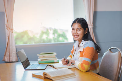 Portrait of a smiling young woman sitting on table