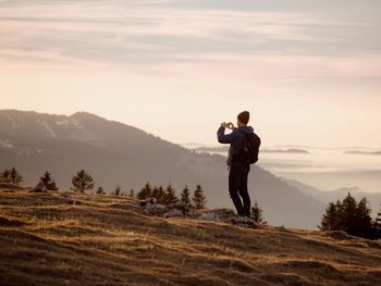 Man photographing on landscape against sky