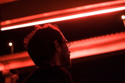 Side view of man looking away against illuminated background