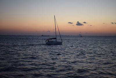 Silhouette sailboat in sea against sky during sunset