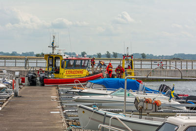 Boats moored at harbor against sky