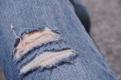 Midsection of person wearing torn jeans at home