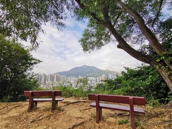 Empty chairs and table against trees and mountains against sky