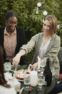 Smiling woman cutting cake in garden