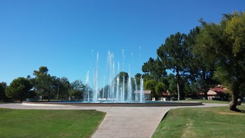 Fountain in park against clear blue sky