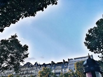 Low angle view of trees and buildings against sky