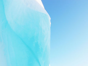 Low angle view of frozen sea against clear blue sky