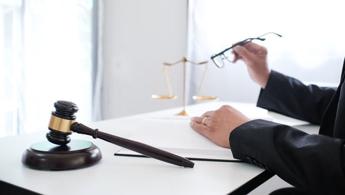 Cropped hand of lawyer holding eyeglasses in courthouse