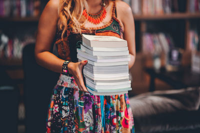 Midsection of woman holding book in library