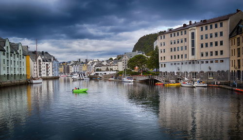 Sailboats moored on river by buildings in city against sky