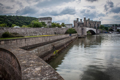 Arch bridge over river against cloudy sky