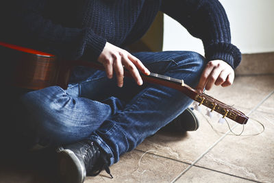 Low section of man removing guitar strings