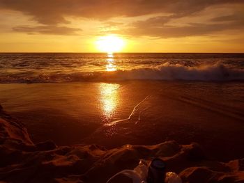 Low section of person on beach against sky during sunset