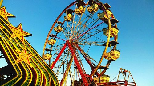 Low angle view of ferris wheel against clear blue sky
