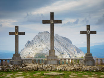 Cross at cemetery against sky