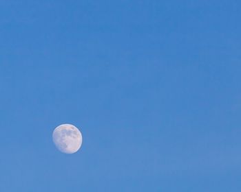 Low angle view of moon against clear blue sky