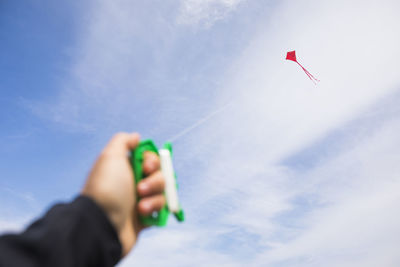 Selective focus on red kite in the air, person holding on.