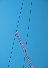 Low angle view of crane against clear blue sky