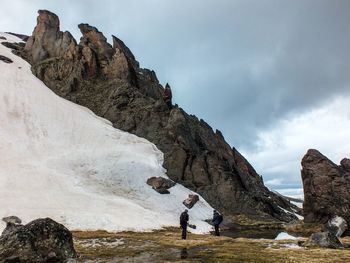 Rear view of people hiking on mountain against sky