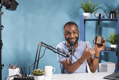 Portrait of man using mobile phone while sitting on table