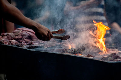 Cropped hand preparing food on barbecue grill