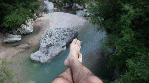 Low section of person sitting over river in forest