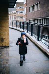 Full length of man standing on footpath against buildings in city