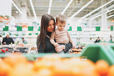 Young woman with baby boy standing in supermarket
