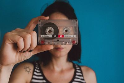 Midsection of woman holding camera against blue background